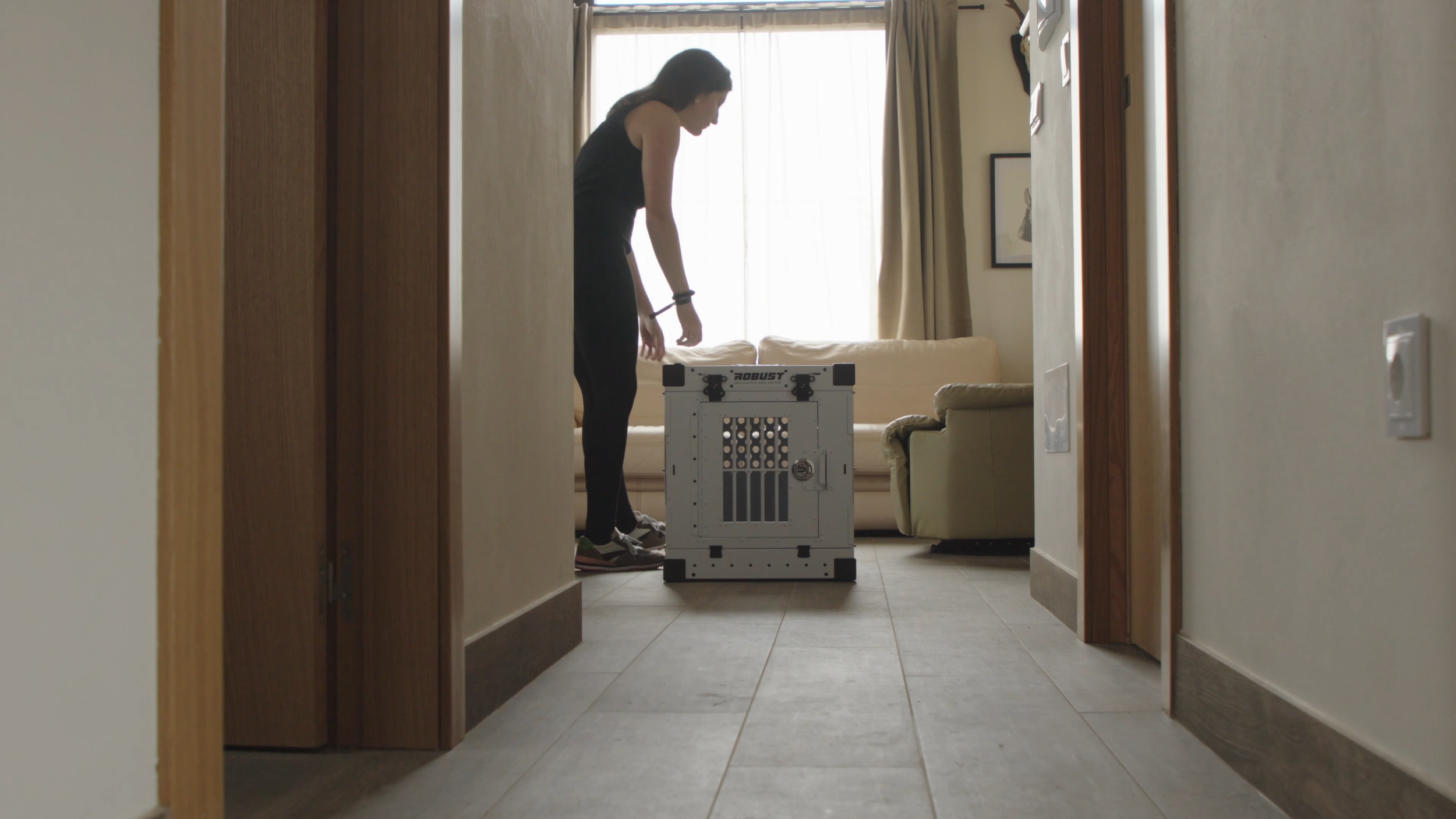 Woman setting up a white Robust size M collapsible dog crate at home with her dog, then placing it in the car.