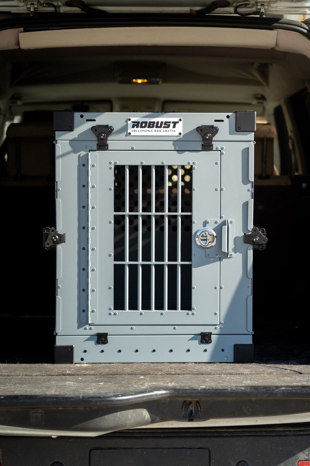 Front view of the grey Robust collapsible dog crate installed in the boot of a car.